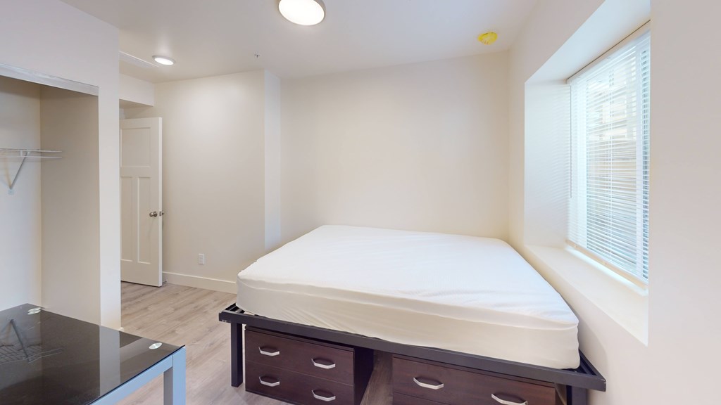 A bedroom with a bed, nightstand, and a glass table.